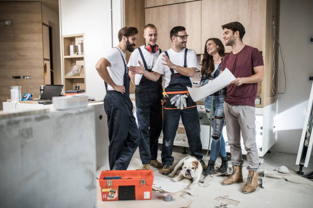  A team gathered in a kitchen with construction supplies, planning a bathroom remodel together.

